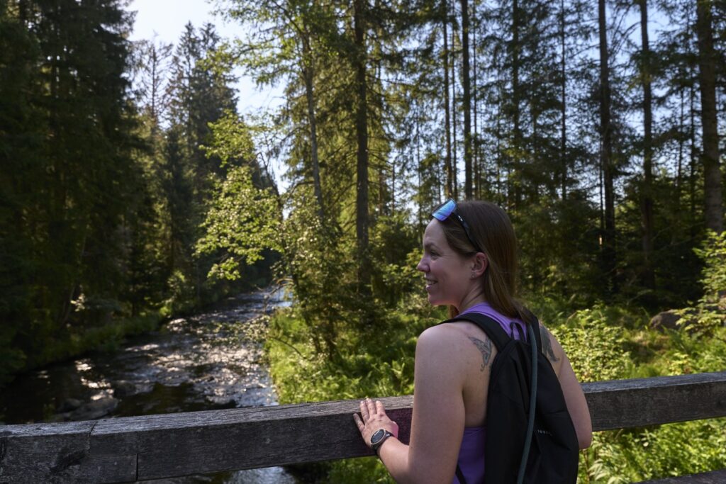 Wanderin an der Bruecke am Bergbach