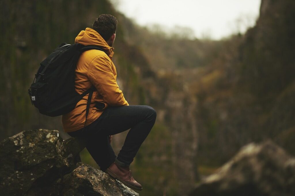 Wanderer sitzt allein auf einem Felsen vor einem Wasserfall