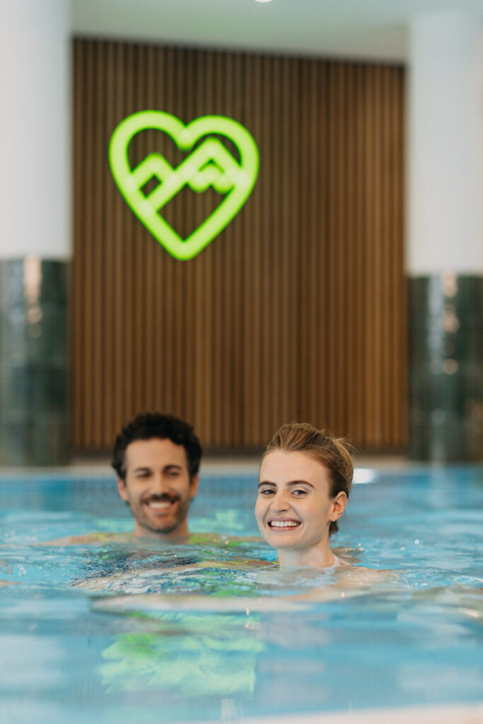 Lächelndes Paar im Innenpool des BERGlässig Hotel Bodenmais