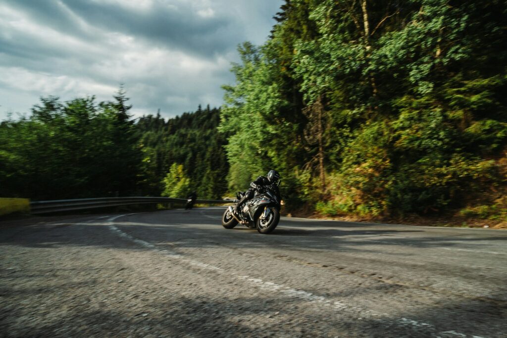 Motorradfahrer in einer Kurve auf einer Waldstraße