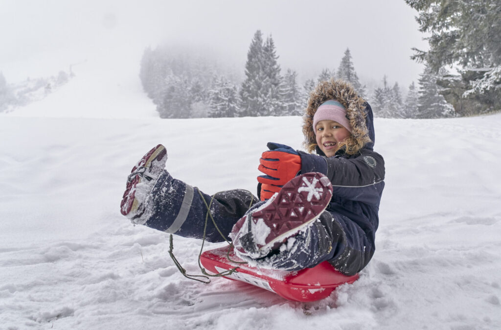 Kind beim Rodeln im Schnee bei Bodenmais