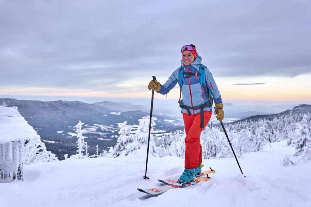 Skitourengeherin am Gipfel mit Panoramablick im Bayerischen Wald