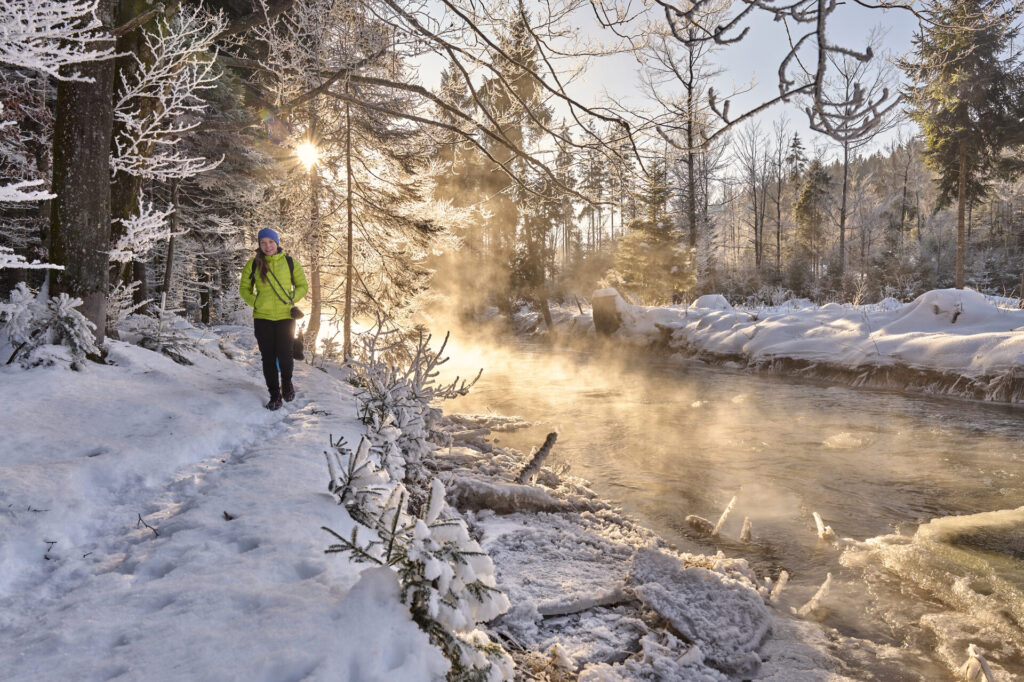 Winterwanderer am dampfenden Bach im Bayerischen Wald